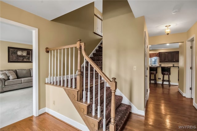 staircase featuring wood finished floors and baseboards