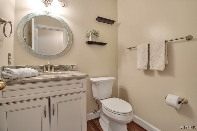 bathroom with wood finished floors, vanity, toilet, and baseboards