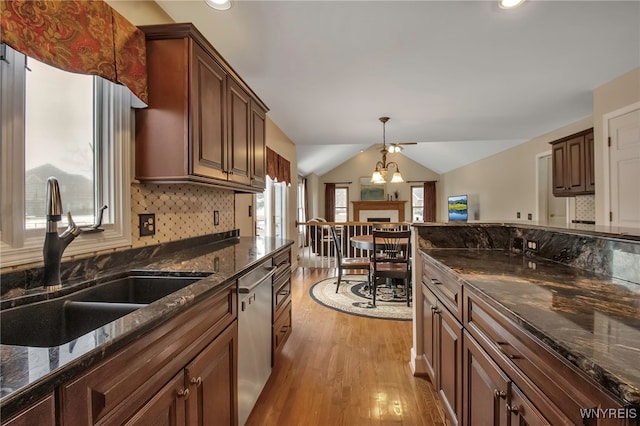 kitchen featuring decorative backsplash, dishwasher, lofted ceiling, light wood-style floors, and a sink