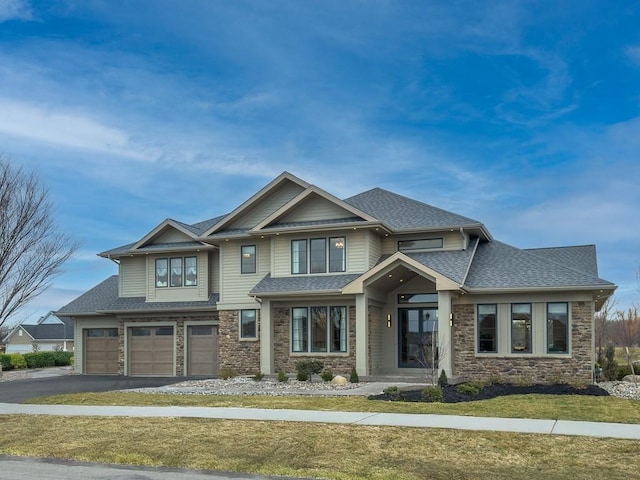 view of front of property featuring aphalt driveway, roof with shingles, an attached garage, stone siding, and a front lawn