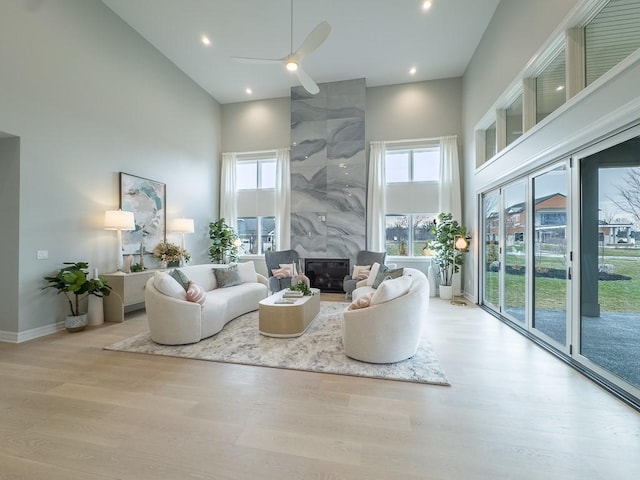 living area with a wealth of natural light, a high ceiling, a fireplace, and wood finished floors