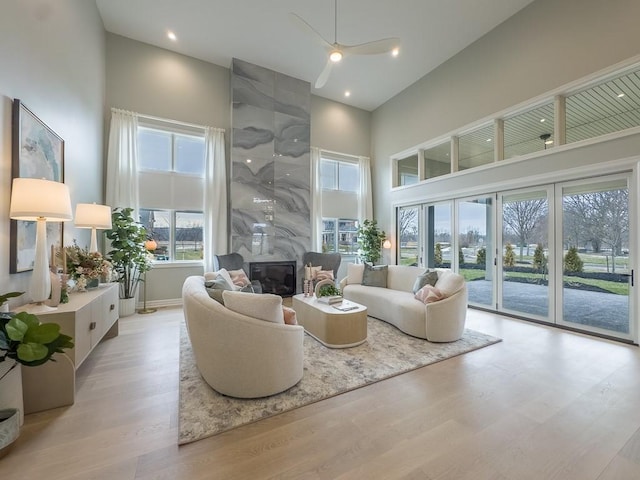 sitting room featuring a high end fireplace, light wood-style flooring, a high ceiling, and recessed lighting