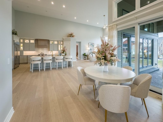 dining room with light wood finished floors, a high ceiling, baseboards, and recessed lighting