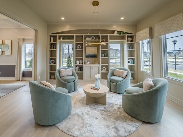 sitting room featuring baseboards, wood finished floors, and a healthy amount of sunlight