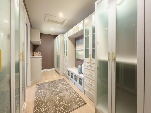 mudroom featuring attic access, light wood-style floors, and baseboards