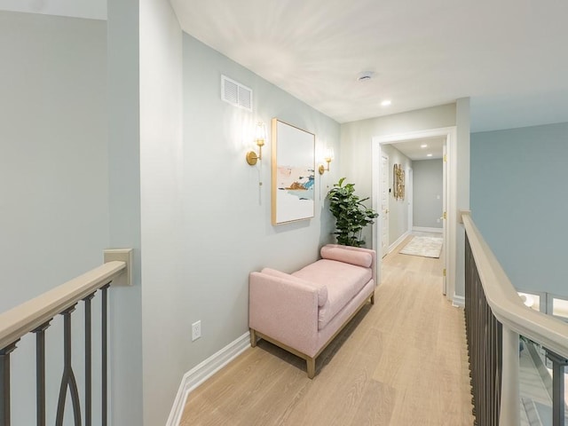 corridor featuring visible vents, light wood-type flooring, an upstairs landing, and baseboards