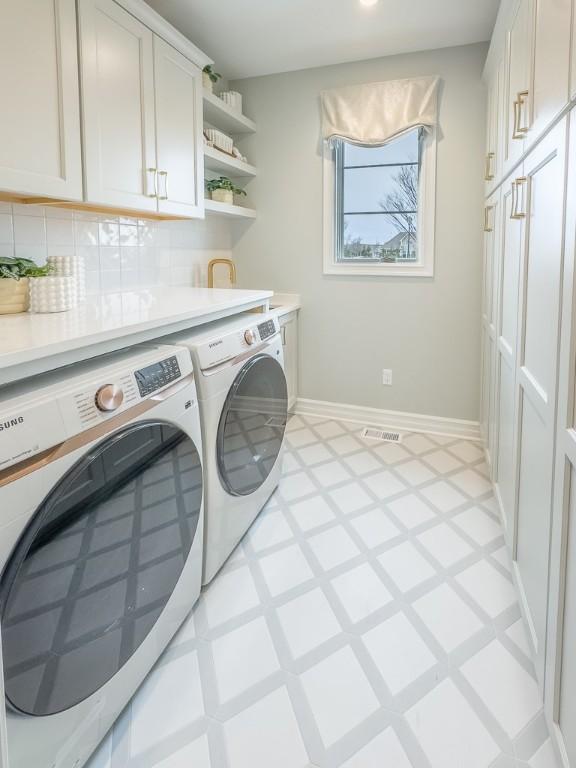 washroom featuring visible vents, baseboards, independent washer and dryer, cabinet space, and light floors