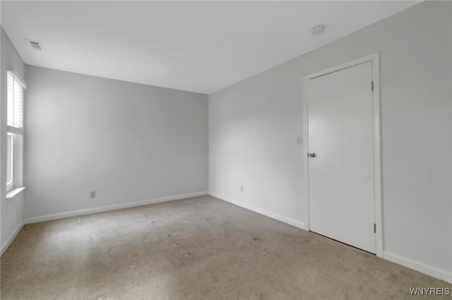 carpeted spare room with visible vents and baseboards