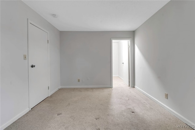 unfurnished room with light carpet and baseboards