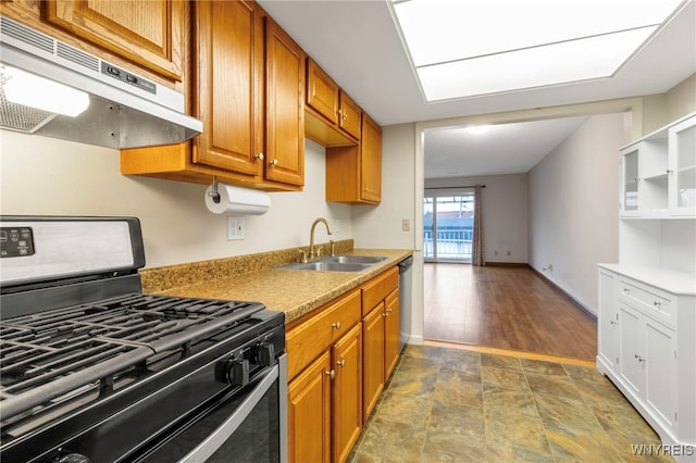 kitchen featuring appliances with stainless steel finishes, brown cabinets, light countertops, under cabinet range hood, and a sink