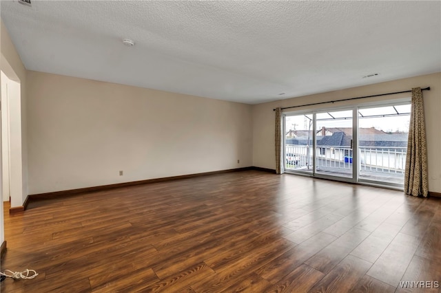 unfurnished room featuring a textured ceiling, dark wood-style flooring, and baseboards