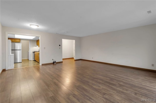 unfurnished living room featuring wood finished floors, visible vents, and baseboards