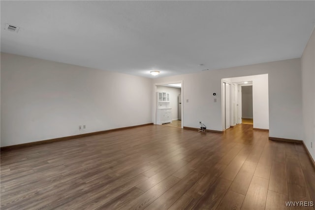 unfurnished room with visible vents, baseboards, and wood finished floors