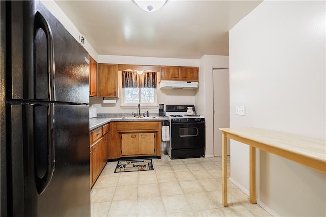 kitchen featuring under cabinet range hood, a sink, freestanding refrigerator, brown cabinets, and gas range