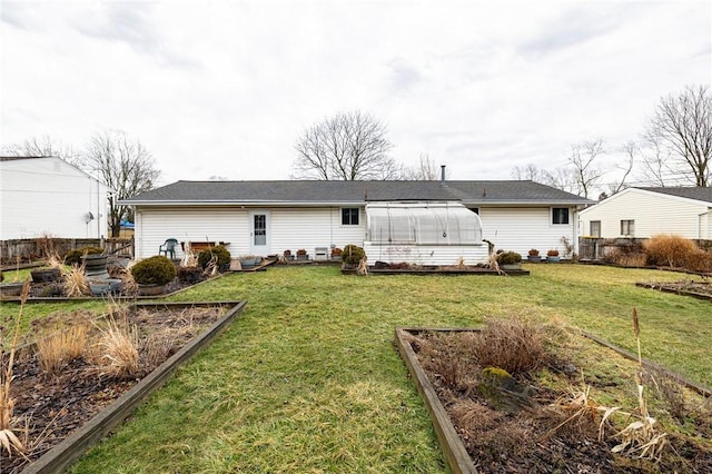 back of house with a yard, fence, and a garden