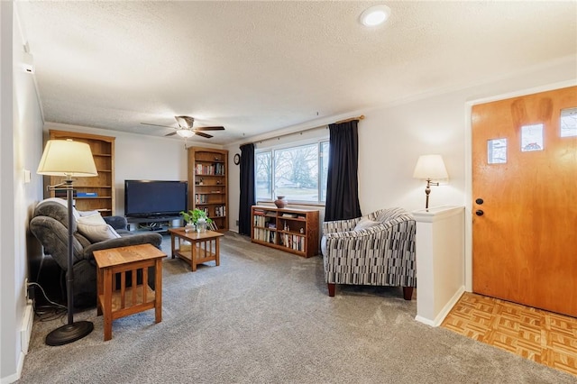 living room with carpet floors, ceiling fan, a textured ceiling, and baseboards