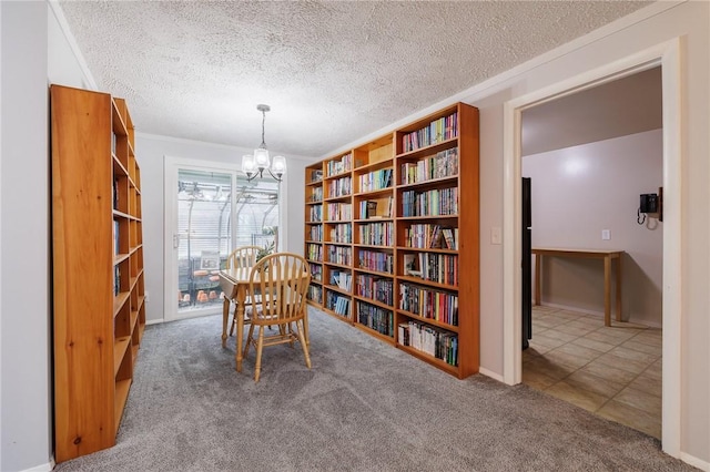 sitting room featuring a textured ceiling, ornamental molding, wall of books, carpet, and an inviting chandelier