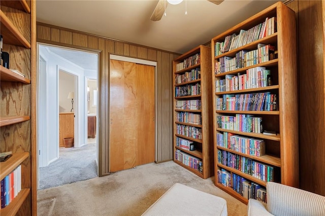 sitting room with carpet, ceiling fan, and wooden walls