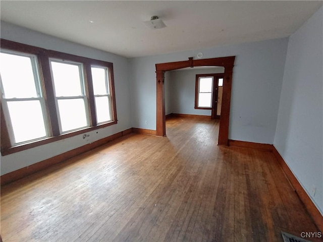 spare room featuring wood-type flooring, visible vents, and baseboards