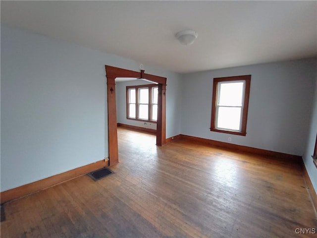 spare room with baseboards, visible vents, and wood finished floors