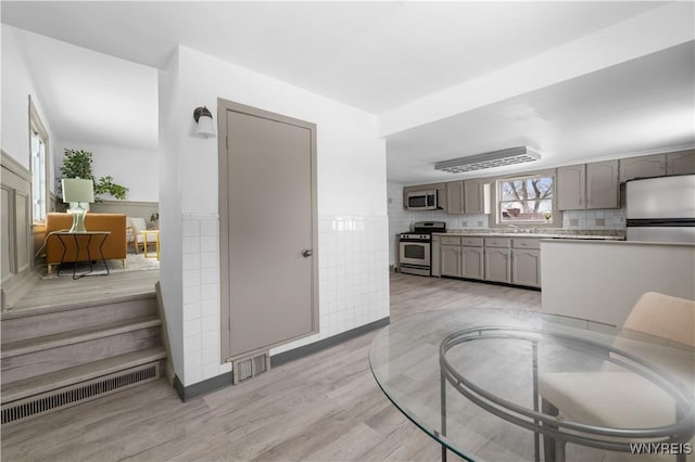 kitchen featuring light wood-style flooring, gray cabinetry, stainless steel appliances, visible vents, and light countertops