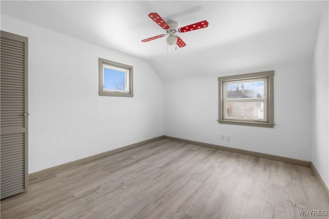 empty room with vaulted ceiling, light wood-type flooring, a wealth of natural light, and baseboards