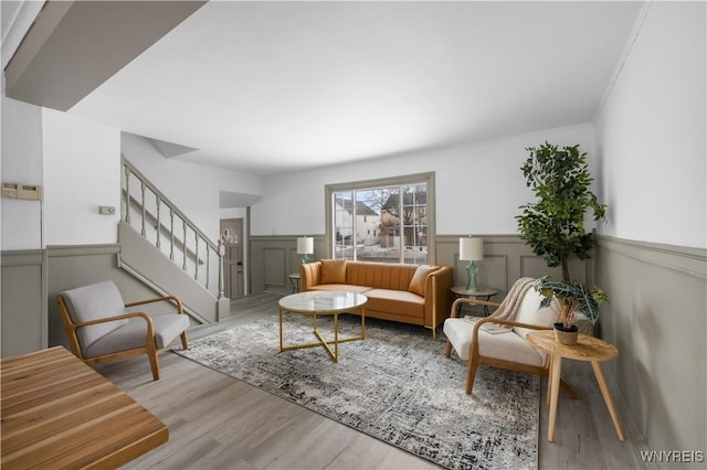 living area featuring a wainscoted wall, stairs, and wood finished floors