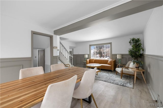 dining area featuring wood finished floors, wainscoting, and stairs