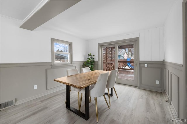 dining room with light wood-type flooring, visible vents, and a wealth of natural light