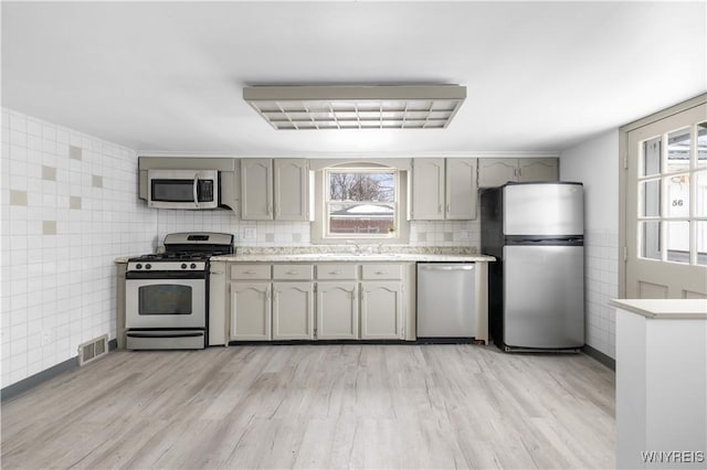 kitchen with light countertops, appliances with stainless steel finishes, gray cabinets, and a wealth of natural light