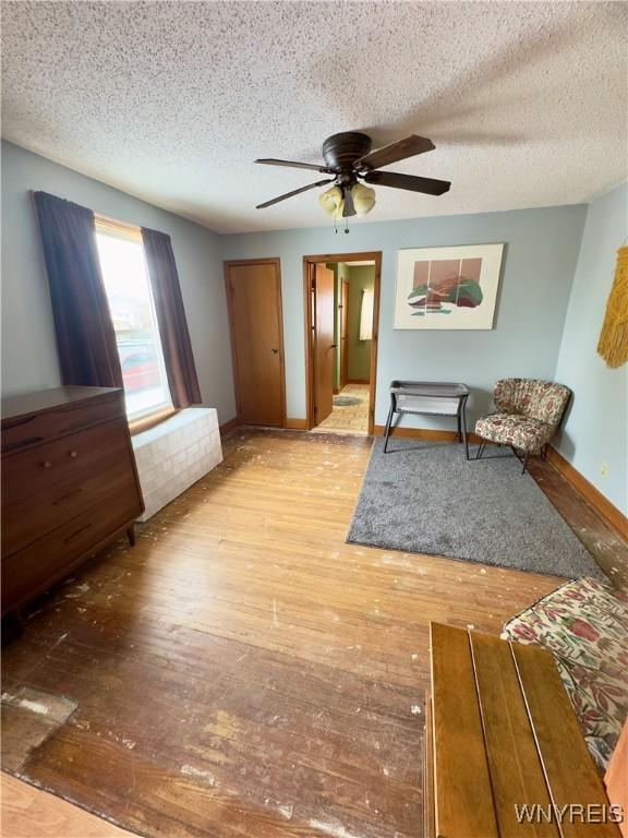 unfurnished bedroom featuring ceiling fan, a textured ceiling, baseboards, and hardwood / wood-style flooring