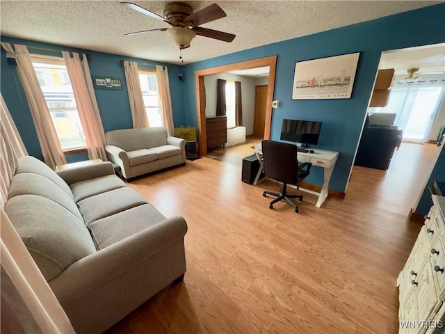 office featuring light wood-style floors, a textured ceiling, and a ceiling fan