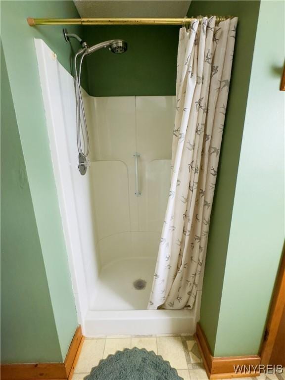 bathroom featuring a shower stall, baseboards, and tile patterned flooring