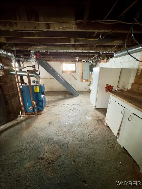 basement featuring freestanding refrigerator and electric panel