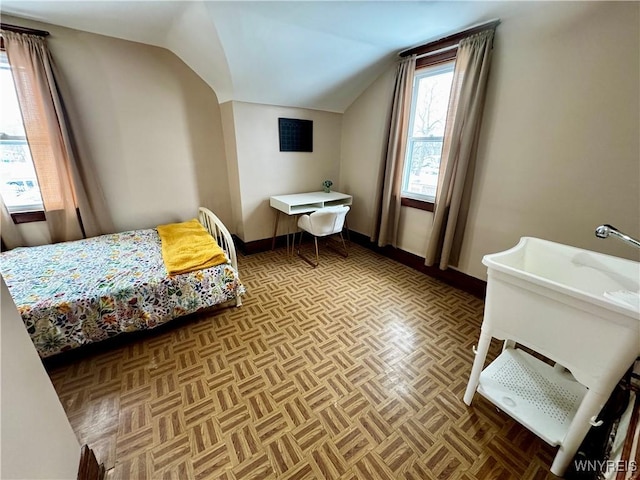 bedroom featuring lofted ceiling and baseboards