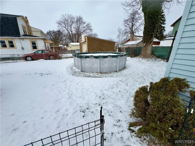 yard layered in snow featuring a covered pool and fence