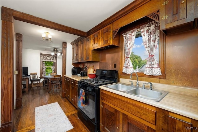 kitchen with a ceiling fan, black gas range oven, dark wood-style flooring, light countertops, and a sink