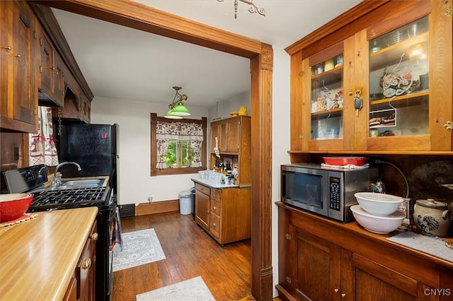 kitchen featuring glass insert cabinets, stainless steel microwave, dark wood-type flooring, and gas stove