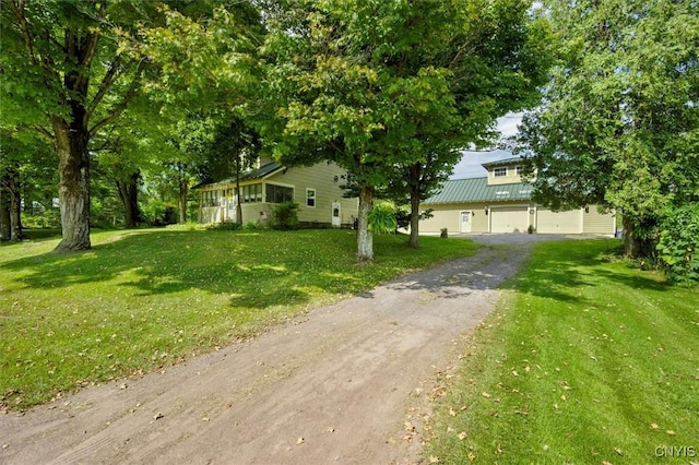 view of front of property with metal roof, driveway, a front lawn, and an attached garage