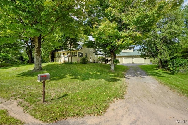 obstructed view of property with a garage, a front yard, metal roof, and driveway