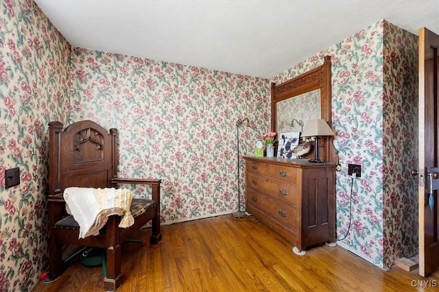 living area with wood finished floors and wallpapered walls