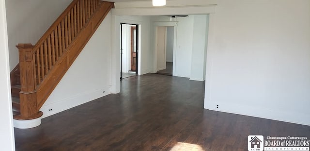 spare room featuring dark wood-type flooring and stairs