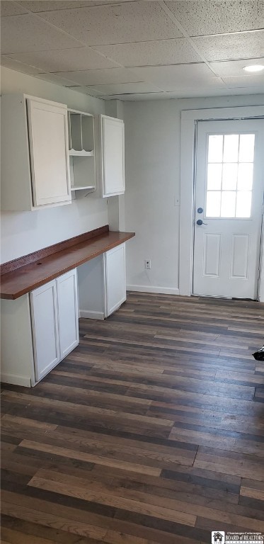 kitchen featuring dark wood-type flooring, butcher block countertops, white cabinetry, and baseboards