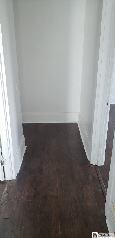 corridor featuring baseboards and wood finished floors