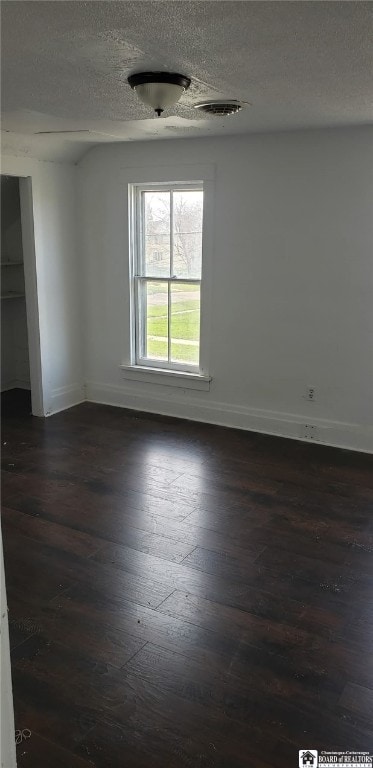 unfurnished room featuring a textured ceiling, dark wood finished floors, visible vents, and baseboards