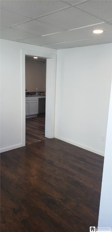 unfurnished room featuring a paneled ceiling, dark wood-style flooring, and baseboards