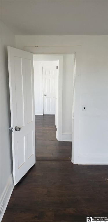 hall with dark wood-type flooring and baseboards