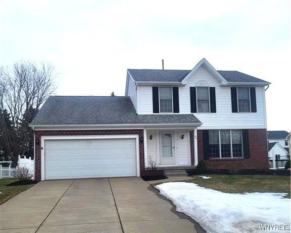 traditional home with brick siding, driveway, and an attached garage