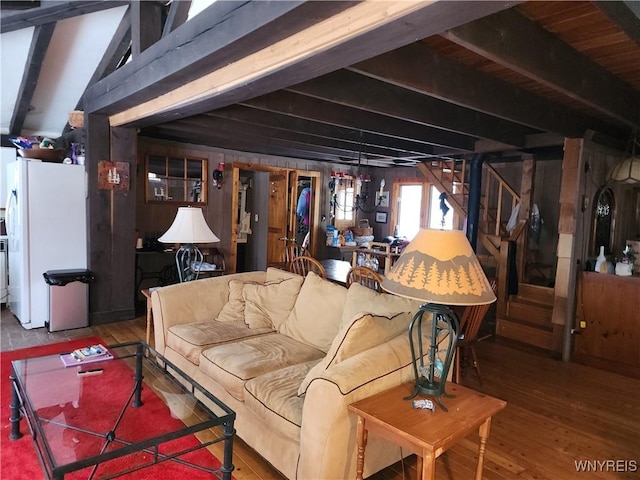 living room with beamed ceiling, stairs, and wood finished floors