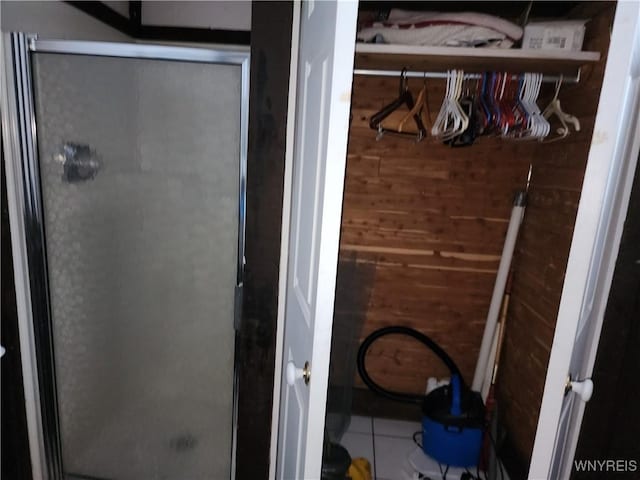 bathroom featuring a shower stall and wood walls